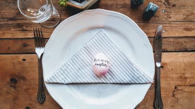 Easter egg on a white plate with fork and knife on a wooden table