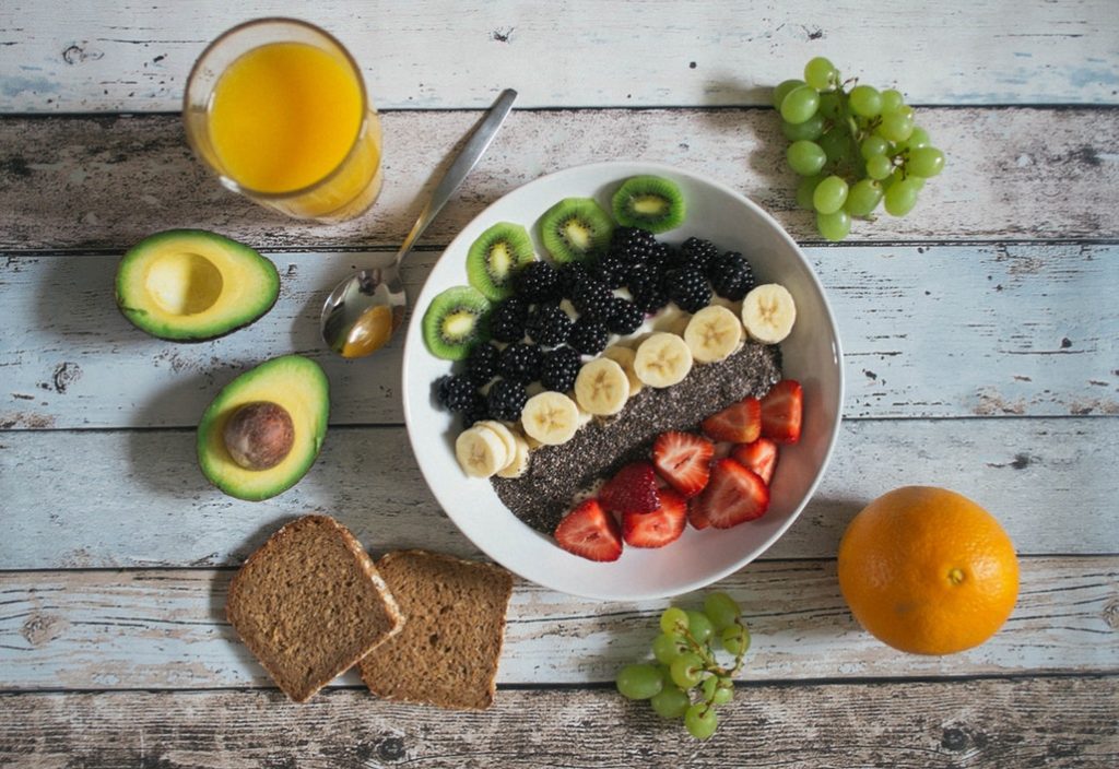 A healthy breakfast bowl with toast, avocado, and orange juice