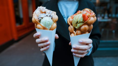 Hands holding two bubble waffles with ice cream
